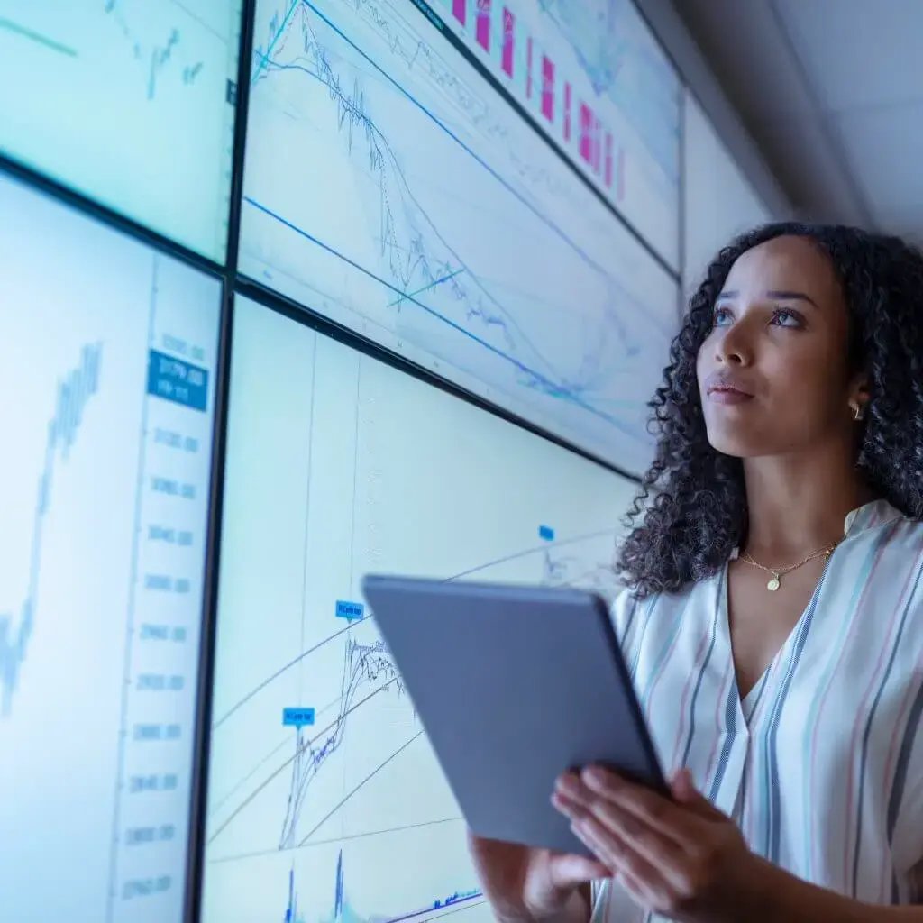 A woman is looking at monitors with different charts