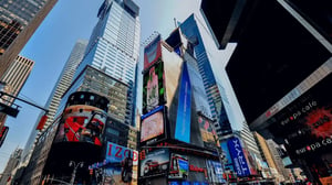 Urban scene with tall buildings and large digital billboards displaying advertisements.