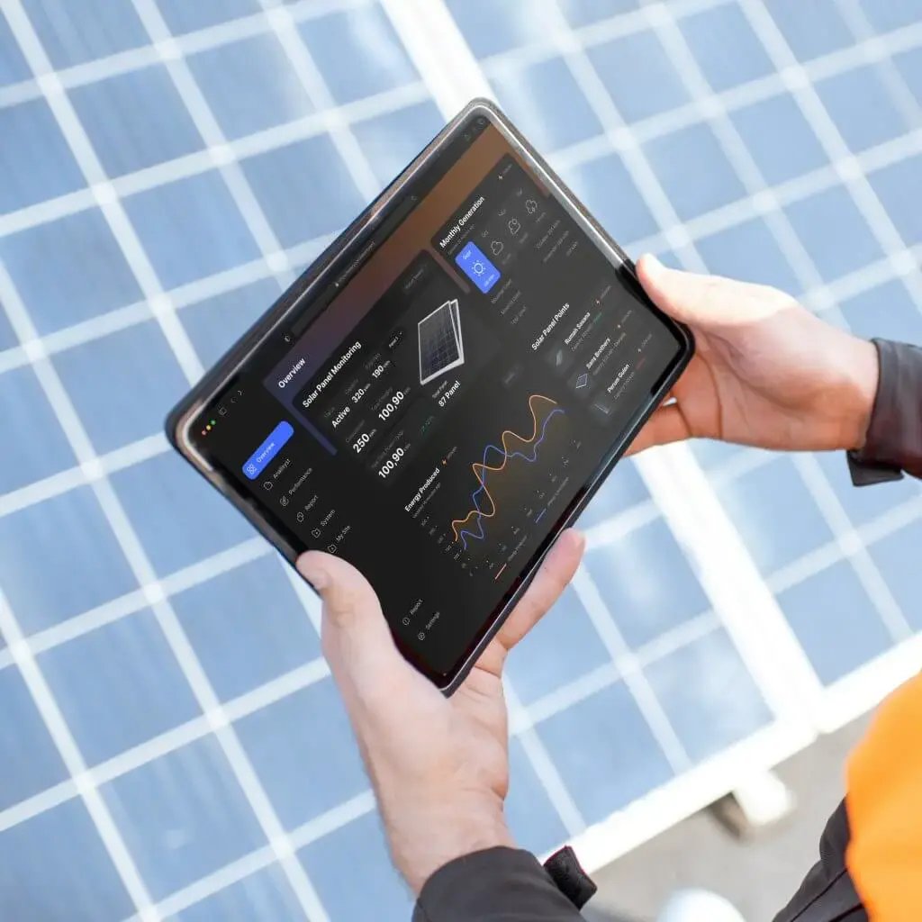 Person holding a tablet displaying solar panel real-time data in front of solar panels