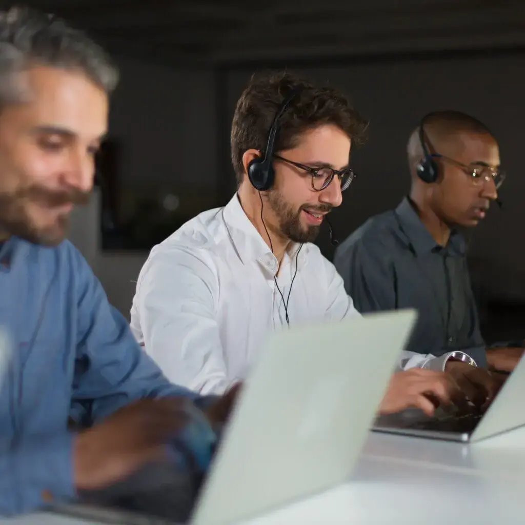 Three men wearing headphones working on laptops